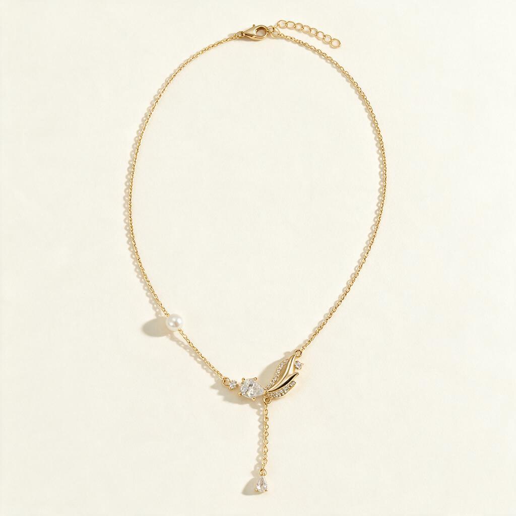 Gold-tone necklace with pear crystal leaf pendant and pearl on ivory background