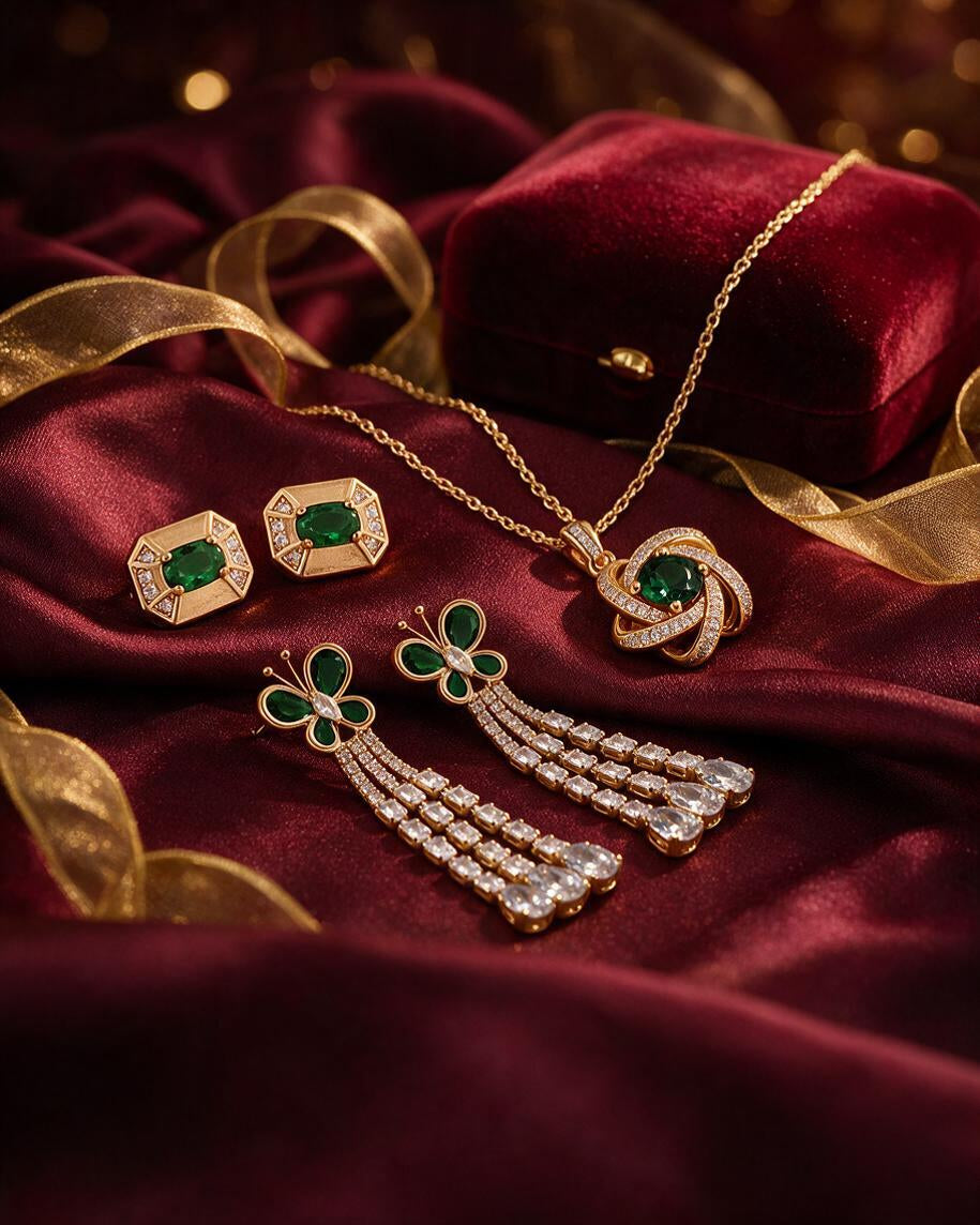 Emerald green stone studs, green butterfly drops and a green pendant necklace on maroon velvet